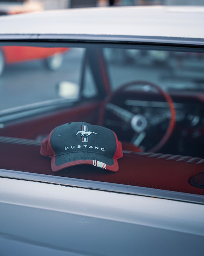 A Mustang cap rests on the dashboard of a vintage car in İzmir, Türkiye, capturing a retro vibe.
